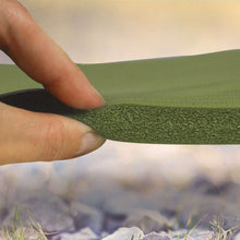 Green foam sleeping pad mat with textured surface and raised edge