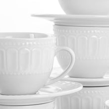 White ceramic mugs with embossed sides and saucers, close-up view