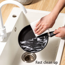 Black nonstick skillet being wiped clean with a cloth, riveted handle