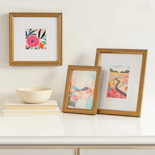 Gold beaded tabletop picture frames set on display, various small prints