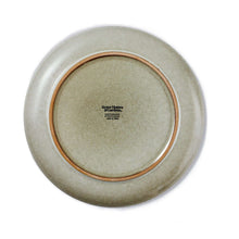 Cream ceramic dinner plate with brand mark on underside and tan outer ring
