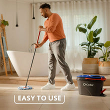 Spin mop with microfiber pad and red handle on hardwood floor during use