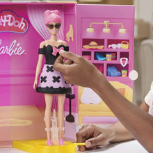 Fashion doll on yellow base wearing black dress with pink bow and heart print