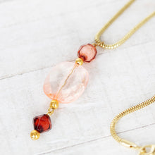 Gold-tone chain necklace with pink and red glass beads and faceted spacers