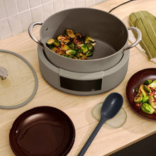 Beige multi-cooker pot with side handles and open lid, cooking basket visible