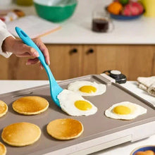 Electric griddle with warming tray, gray surface with frying eggs and pancakes.