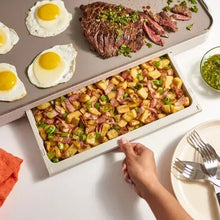 Electric griddle with warming tray, gray top with eggs, steak, and chopped vegetables.