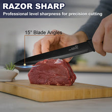 Black chef knife with serrated tip cutting raw meat on a wooden board