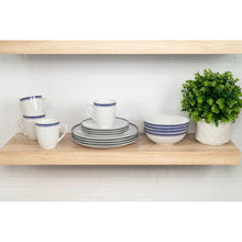Ceramic dinnerware set with stacked plates, bowls, and blue-rimmed mugs