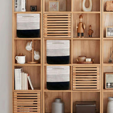 Woven storage baskets, cream with dark base, stacked in wooden shelving cubbies