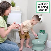 Green toddler potty with open seat being used by a child with caregiver nearby