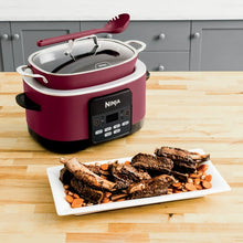 Cherry tarte multi-cooker with open lid and red utensil on the cooker