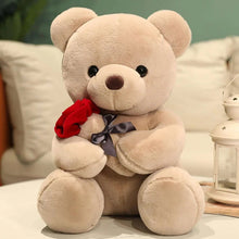 Cream teddy bear plush holding a red rose with a gray ribbon bow