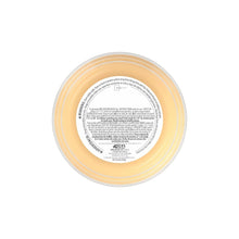 Scented jar candle lid underside with printed label, amber wax in round glass jar