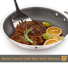 Nonstick fry pan with dark interior and metal spatula over steak and citrus