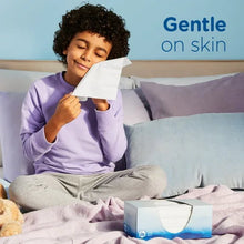 Child holding a white facial tissue while lying on a bed, Ultra Soft