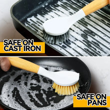 Dish brush with white scrub head and bamboo handle, used on a cast-iron pan