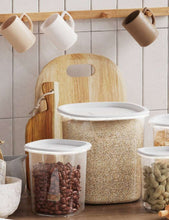 Clear plastic food storage canister with white lid filled with dry grains