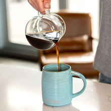 Coffee mug with brewed coffee as carafe pours into it