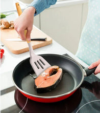 Slotted silicone spatula with bamboo handle lifting salmon from a pan