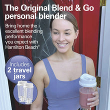 Personal blender with two travel jars and lids, held with one jar ready to drink