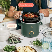 Thyme green manual slow cooker with black lid open, serving tongs holding meatballs