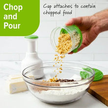 Food chopper cap dispensing chopped food into a glass bowl, white and green