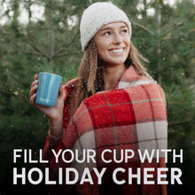 Coffee mug in hand outdoors, plaid sweater and knit beanie visible