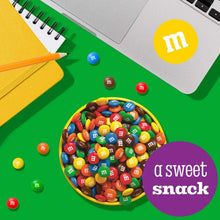 Bowl of colorful M&M candies with scattered candy pieces for snacking