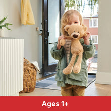 Beige teddy bear plush held up with floppy arms and round brown nose