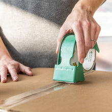 Clear packing tape dispensed from green EZStart dispenser onto cardboard seam