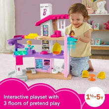Toddler playing with three-level dollhouse playset in pink and purple with figures