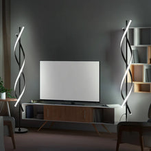 Modern spiral LED floor lamp with curved glowing bars and slim post beside a TV console