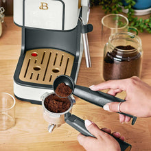 Espresso machine portafilter with ground coffee and filter basket, hands tamping