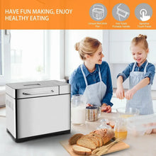 Stainless steel bread maker on kitchen counter with loaf and measuring cup