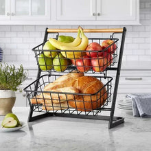 Two-tier fruit basket stand with black wire baskets and bamboo handle, filled with fruit