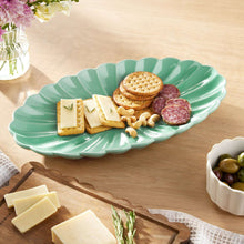 Green leaf-shaped serving tray with crackers and salami