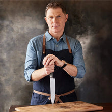 Stainless chef knife with wood handle held upright on a cutting board