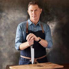 Chef's knife being removed from its sheath by a cook, with wood handle and patterned blade