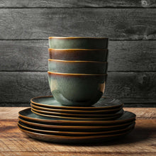 Stacked reactive ceramic mugs and plates in dark teal with brown-gold rim bands