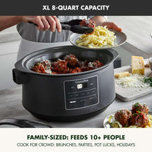 Graphite slow cooker with lid open, cooking pot filled with shredded food