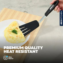 Black silicone slotted spatula lifting food from a cutting board