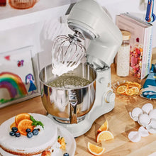 White stand mixer with stainless bowl and balloon whisk mixing batter