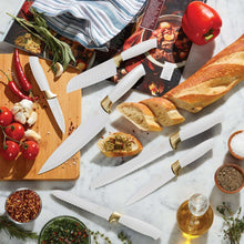Stainless steel knives with white handles and gold collars on a cutting board