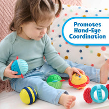 Toddler holding a blue sensory ball; lion and turtle balls beside