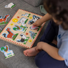 Child placing farm animal peg pieces on a sound puzzle board