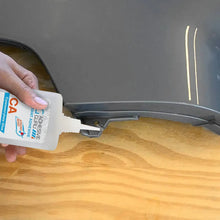 Cyanoacrylate glue bottle dispensing adhesive onto wooden surface