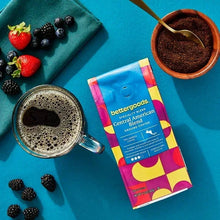 Ground coffee bag with coffee cup and berries on a teal surface