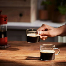 Brewed coffee cups on a counter, with coffee being poured from a mug