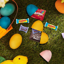 Easter candy pieces on grass: M&M's, Skittles, Starburst, Snickers wrappers